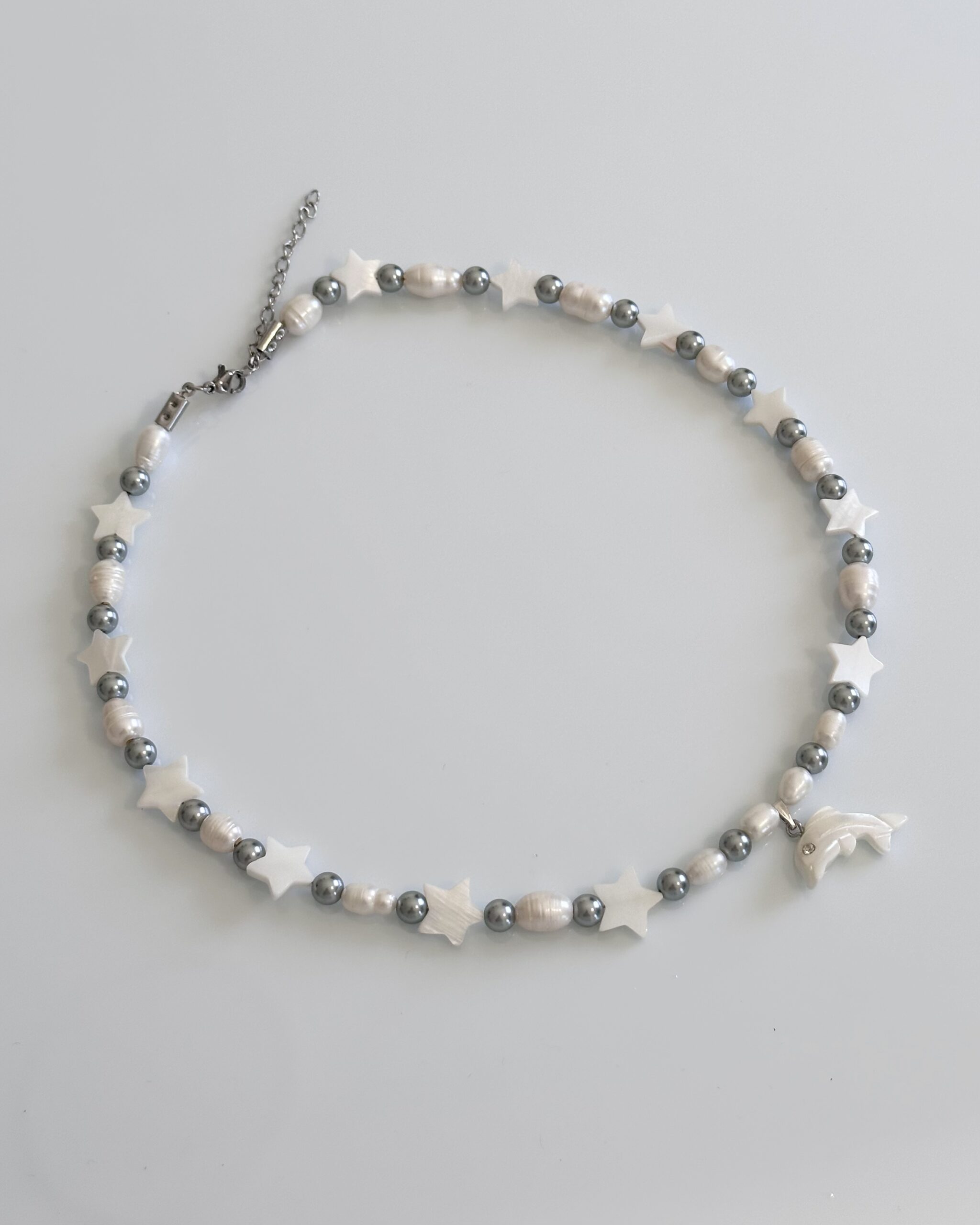 Freshwater pearl and grey glass pearl necklace with mother of pearl stars and a dolphin charm, handmade by NIICA in Lisbon