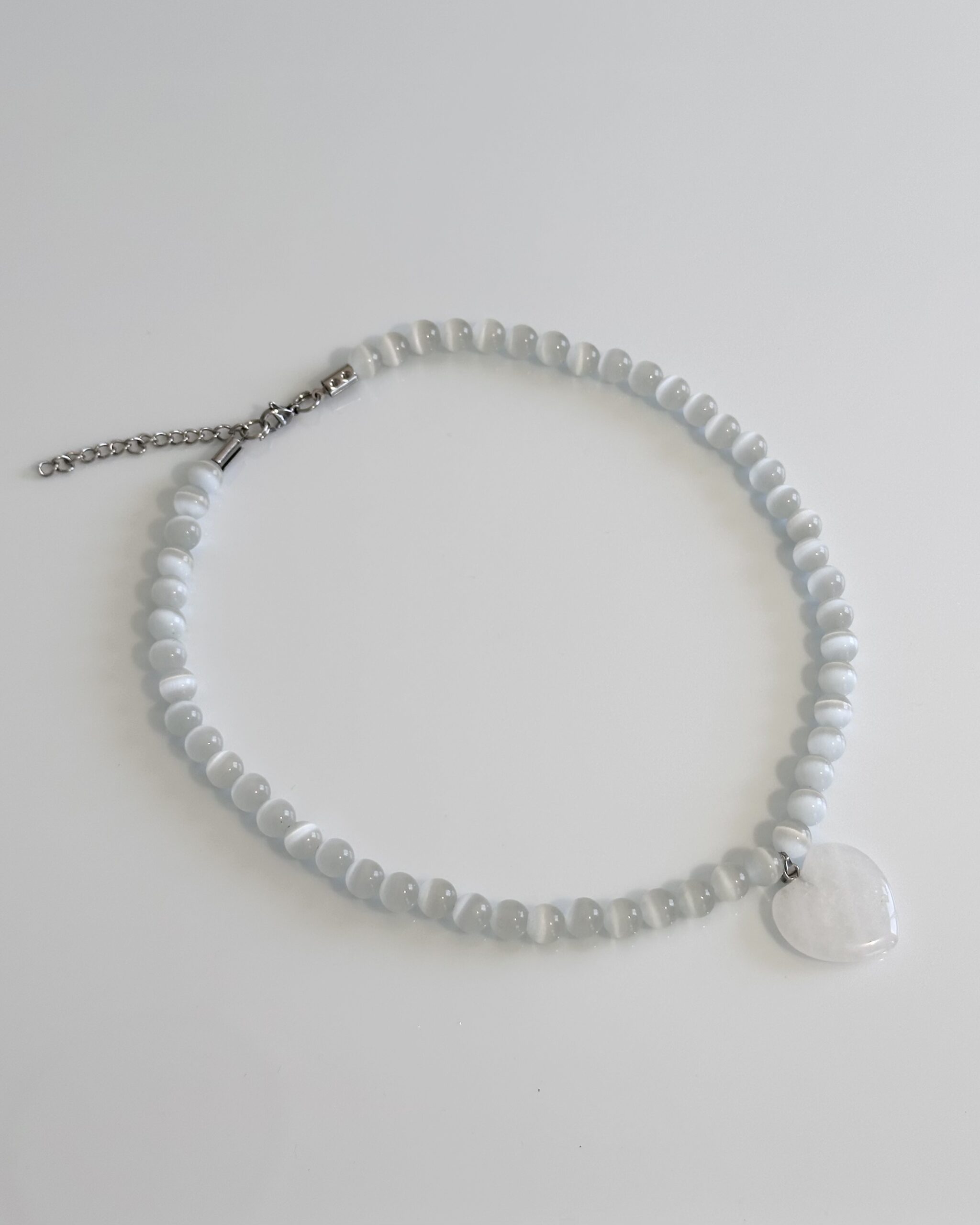 White cat's eye beaded necklace with a quartz heart pendant on an adjustable stainless steel closure, handmade by NIICA in Lisbon